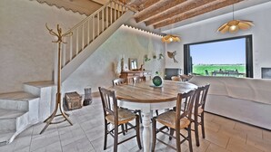 Un comedor con una mesa redonda de madera, cuatro sillas, una escalera y vistas al exterior.