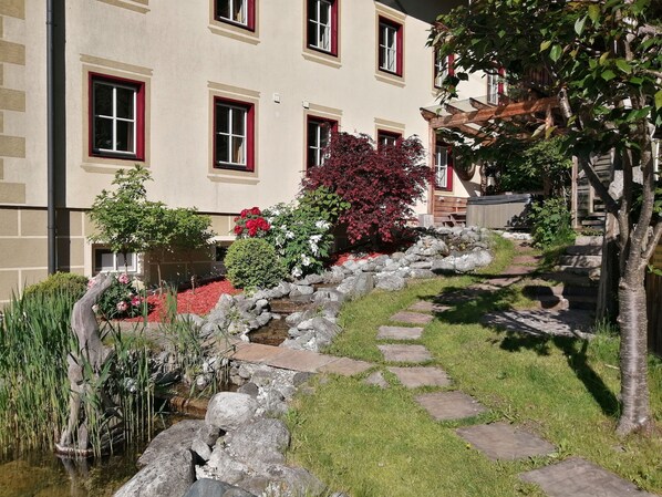 Un bâtiment doté de nombreuses fenêtres, d’un chemin en pierre et d’un petit élément décoratif aquatique.