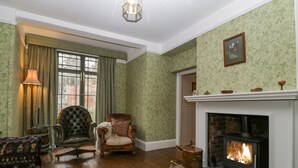 Una habitación tradicional con chimenea, un sillón de cuero, un banco de madera y una lámpara.