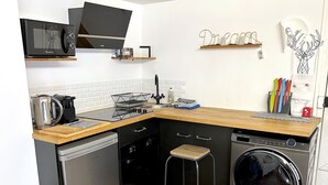 A compact kitchen with a microwave, kettle, and dishwasher. - Loft Varenne (Paris)