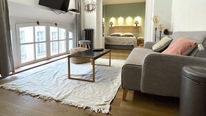 A modern living room with a grey sofa, a small table, and a large window. - Loft Varenne (Paris)