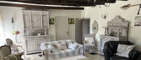 Una sala acogedora con sofá, sillón y otoman, un armario blanco y una chimenea.
