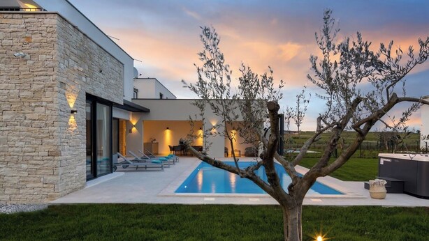 A modern house with a swimming pool, stone exterior, and outdoor seating area.