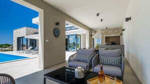 A modern living room with a pool view, a fireplace, and a dining area.