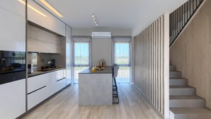 A modern kitchen with a central island, a staircase with a railing, and large windows.