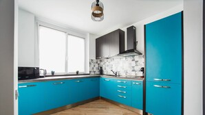 A kitchen with blue cabinets, a microwave, and a window. - Azur Paradise near City Center (Oradea)