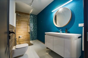 A modern bathroom with a white toilet, a white vanity with a mirror, and a blue accent wall.