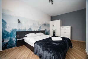 A modern bedroom with a bed, wardrobe, and a mural on the wall.