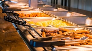 A buffet with various food items including sausages, potatoes, and other dishes. - The Saga Hotel (New Delhi)