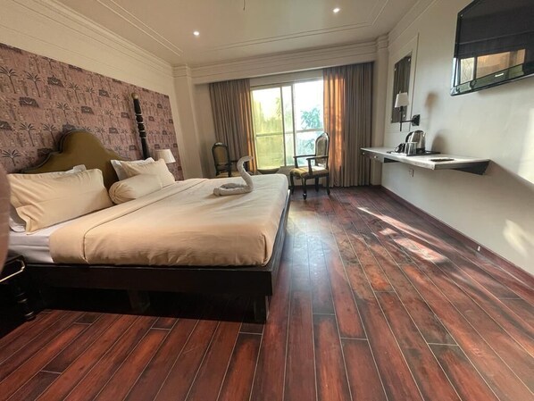 A hotel room with a large bed, a desk with a chair, a window with curtains, and a wall-mounted shelf. - asar Elite Green Park by Orion Hotels (New Delhi)