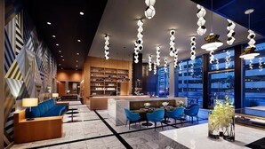 A modern hotel lobby with a reception desk, seating area, and a bar. - 1B1B  DTLA (Los Angeles)
