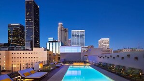 A rooftop pool with lounge chairs and a city skyline in the background. - 1B1B  DTLA (Los Angeles)