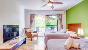 Hotelkamer met een televisie, twee bedden, een plafondventilator, een stoel en uitzicht op de omgeving.