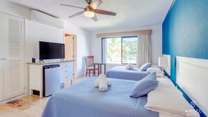 A hotel room with a bed, a desk with a television, a chair, and a window with curtains. - Zona Hotelera Studio with Pool Access, Near Beach (Cancun)