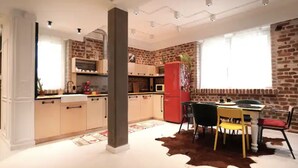 Una cocina moderna con pared de ladrillo, un refrigerador rojo y un comedor con alfombra de cuero de vaca.