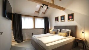 Un dormitorio con una cama grande, un televisor montado en la pared y una ventana con cortinas.