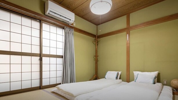 A traditional Japanese-style room with tatami flooring, a sliding shoji screen door, and a bed with white bedding. - 10mins train to Namba, 4mins walk to stn, 2floor Japanese style whole house (大阪市)