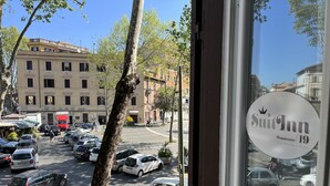 Blick auf einen Parkplatz mit Autos und einem Baum im Vordergrund.