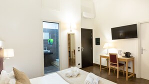 Ein Hotelzimmer mit Bett, Schreibtisch, Stuhl, Fernseher und einer Tür.