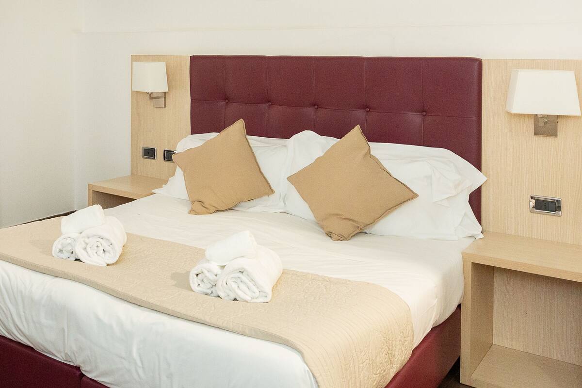 A hotel room with a large bed, two nightstands, and a headboard.
