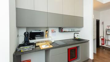 Uma cozinha compacta e moderna, com cafeteira, micro-ondas e uma pia pequena.