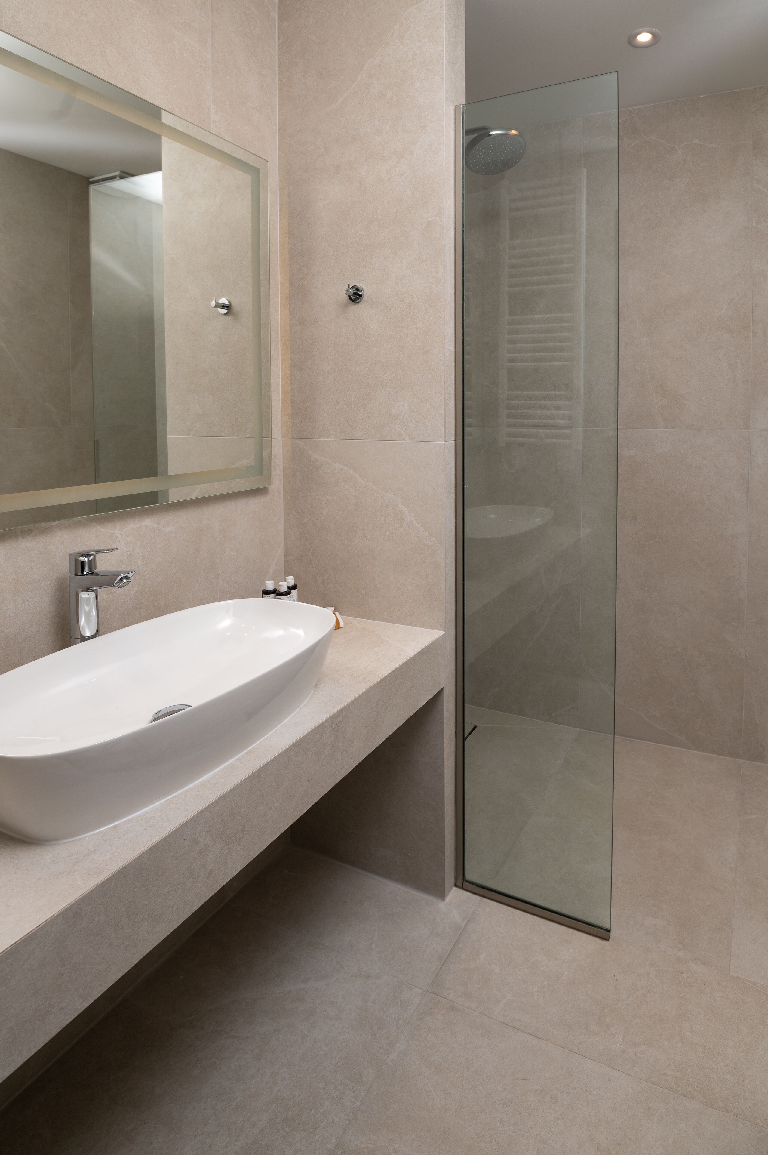 A modern bathroom with a large white sink, a glass shower enclosure, and a mirror above the sink.