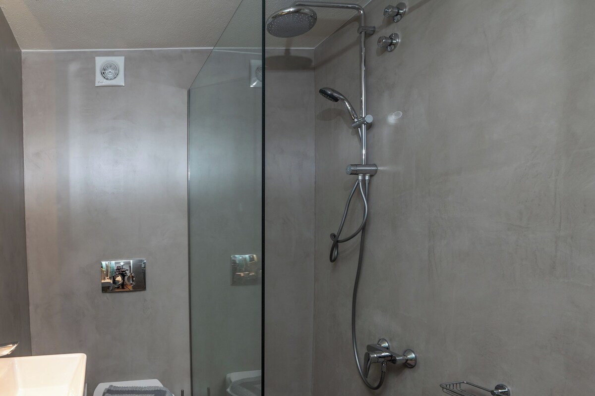 Un baño moderno con ducha envuelta en vidrio, inodoro blanco y lavamanos.