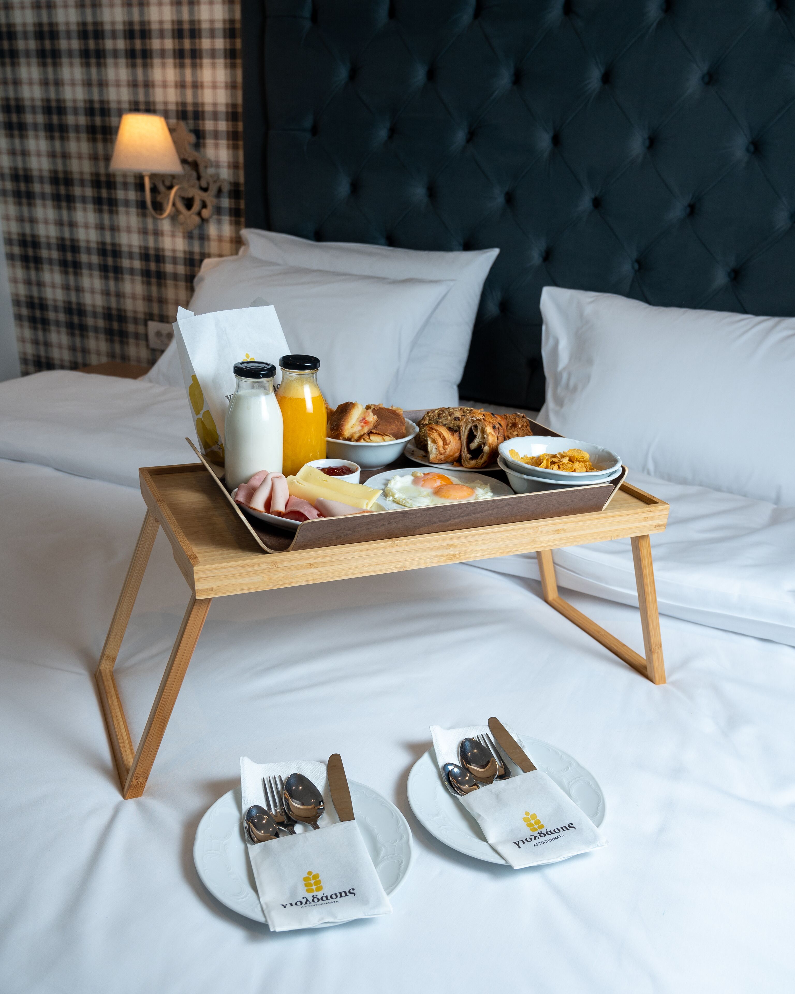 Ein Frühstückswagen mit verschiedenen Speisen auf einem Bett, zusammen mit Besteck und Servietten.