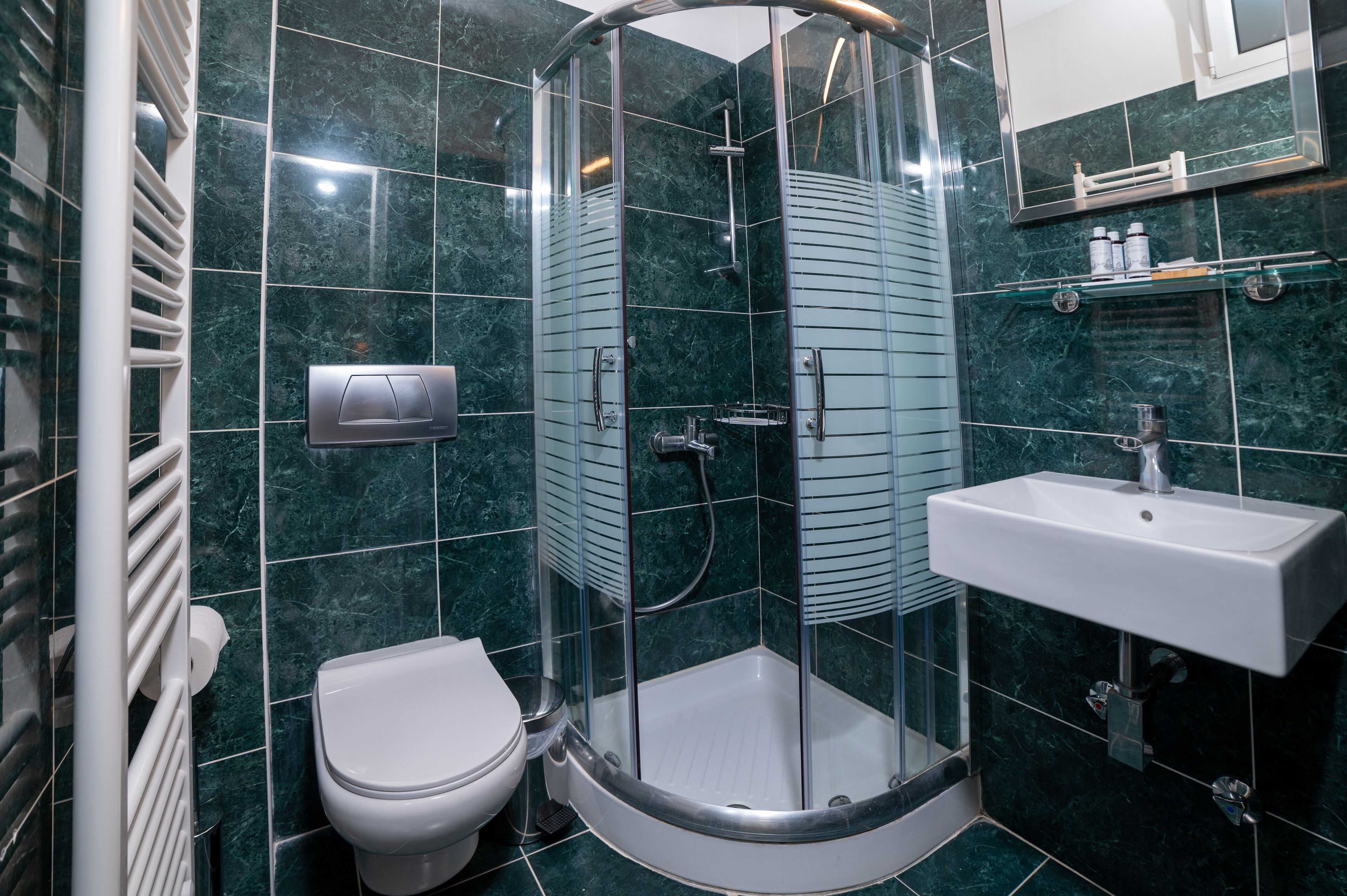 A modern bathroom with a glass-enclosed shower, a white sink, and a toilet.