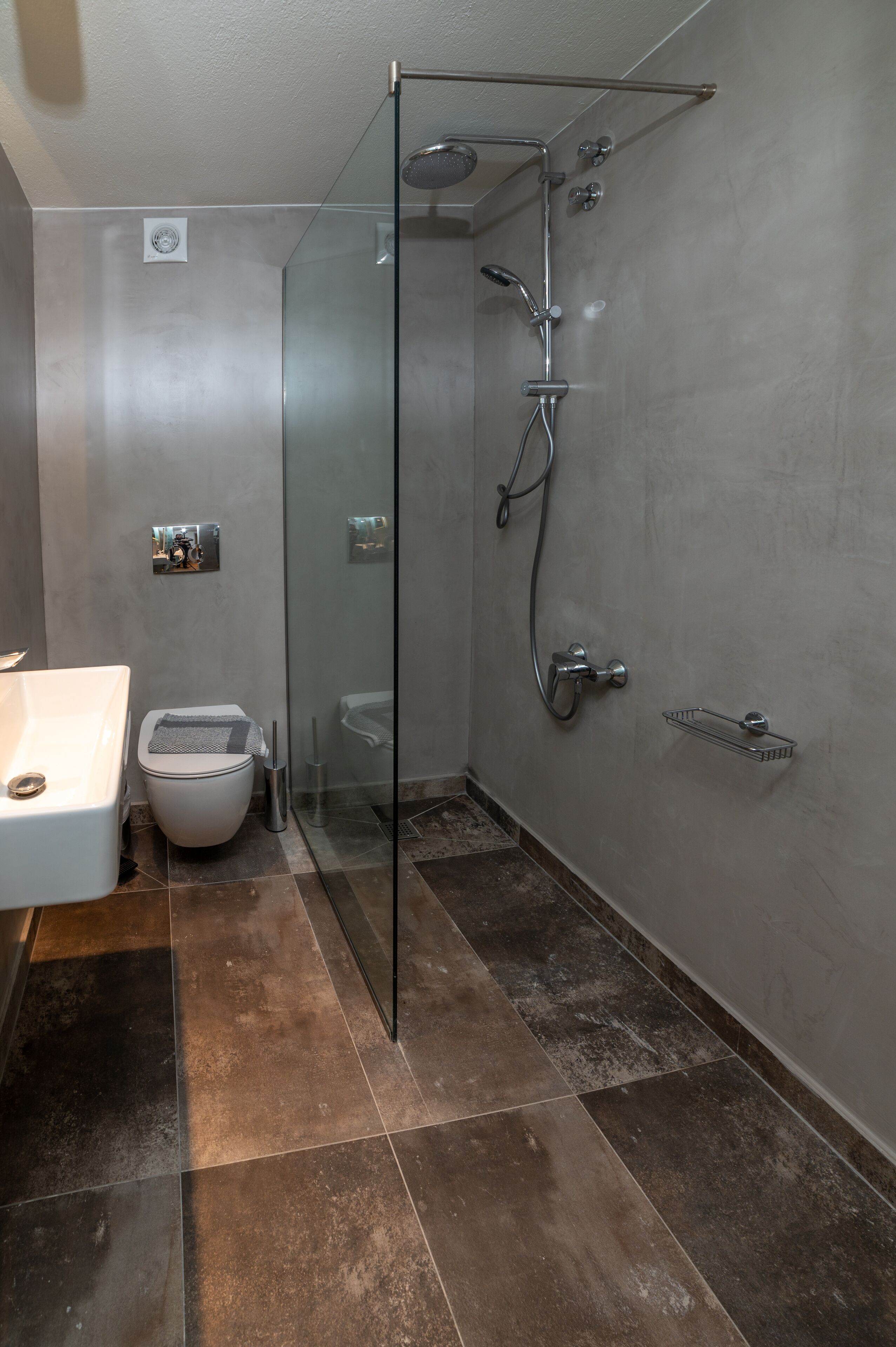 A modern bathroom with a glass-enclosed shower, a white toilet, and a sink.