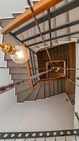 Una escalera con barandilla de madera y un accesorio de luz.