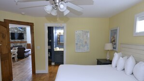 Habitación de hotel con cama, escritorio, silla, televisor y ventilador de techo.