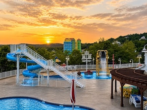 Un parc aquatique avec de nombreux toboggans, une piscine et un coucher de soleil en arrière-plan.