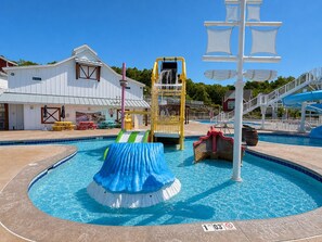 Une piscine avec un toboggan, une aire de jeux et un poste de surveillance pour les sauveteurs.