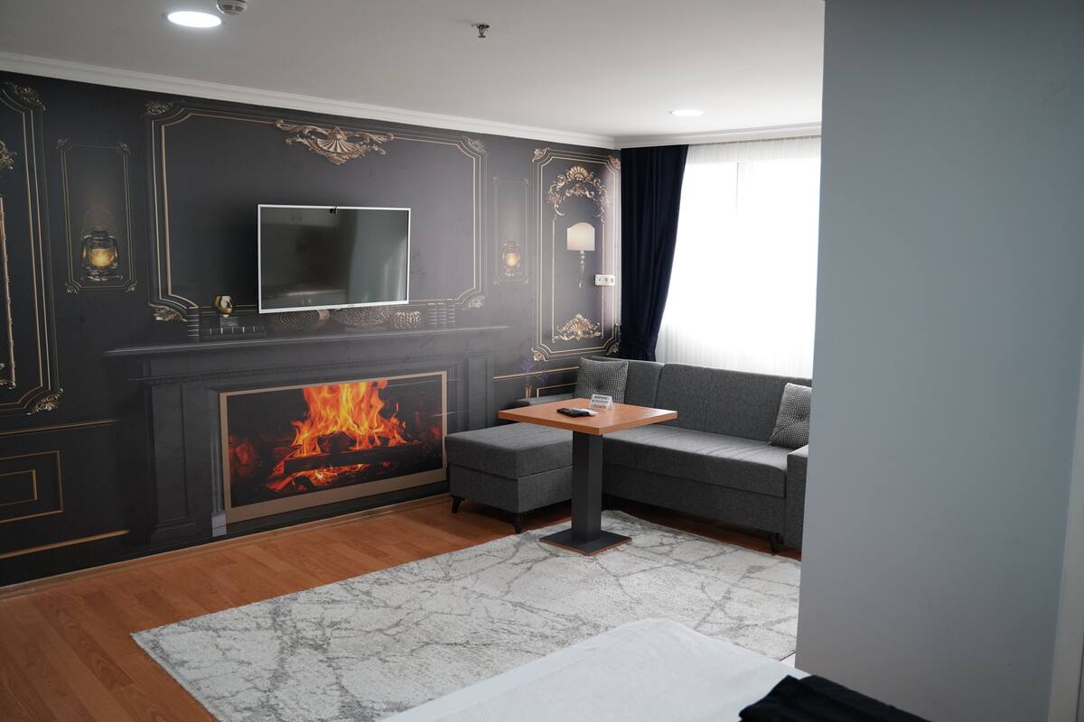 A modern living room with a fireplace, a sofa, a TV, and a table.