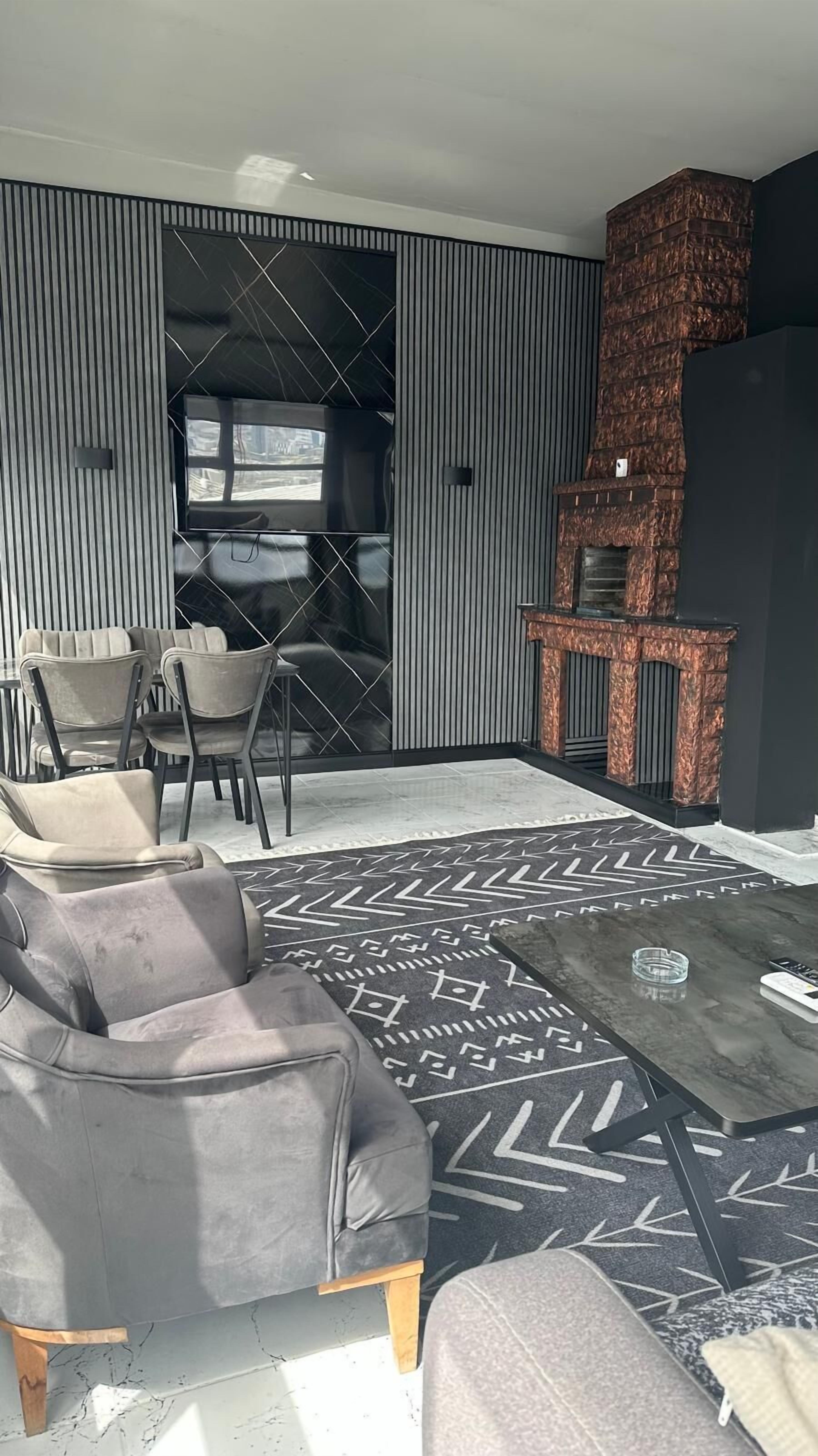 Un salon moderne avec un canapé d’angle, un tapis à motifs et une cheminée.