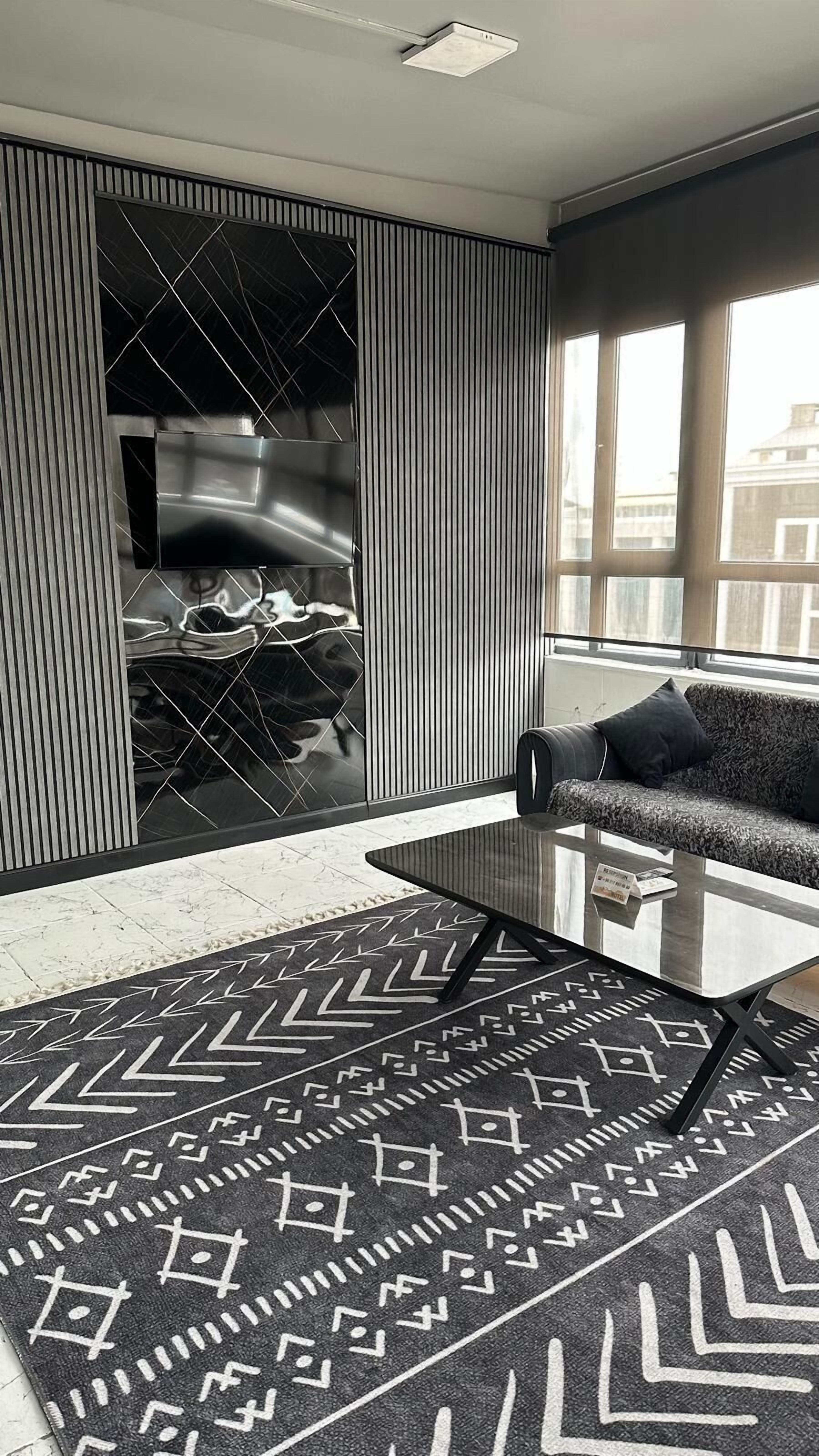 A modern living room with a sofa, coffee table, and patterned rug.