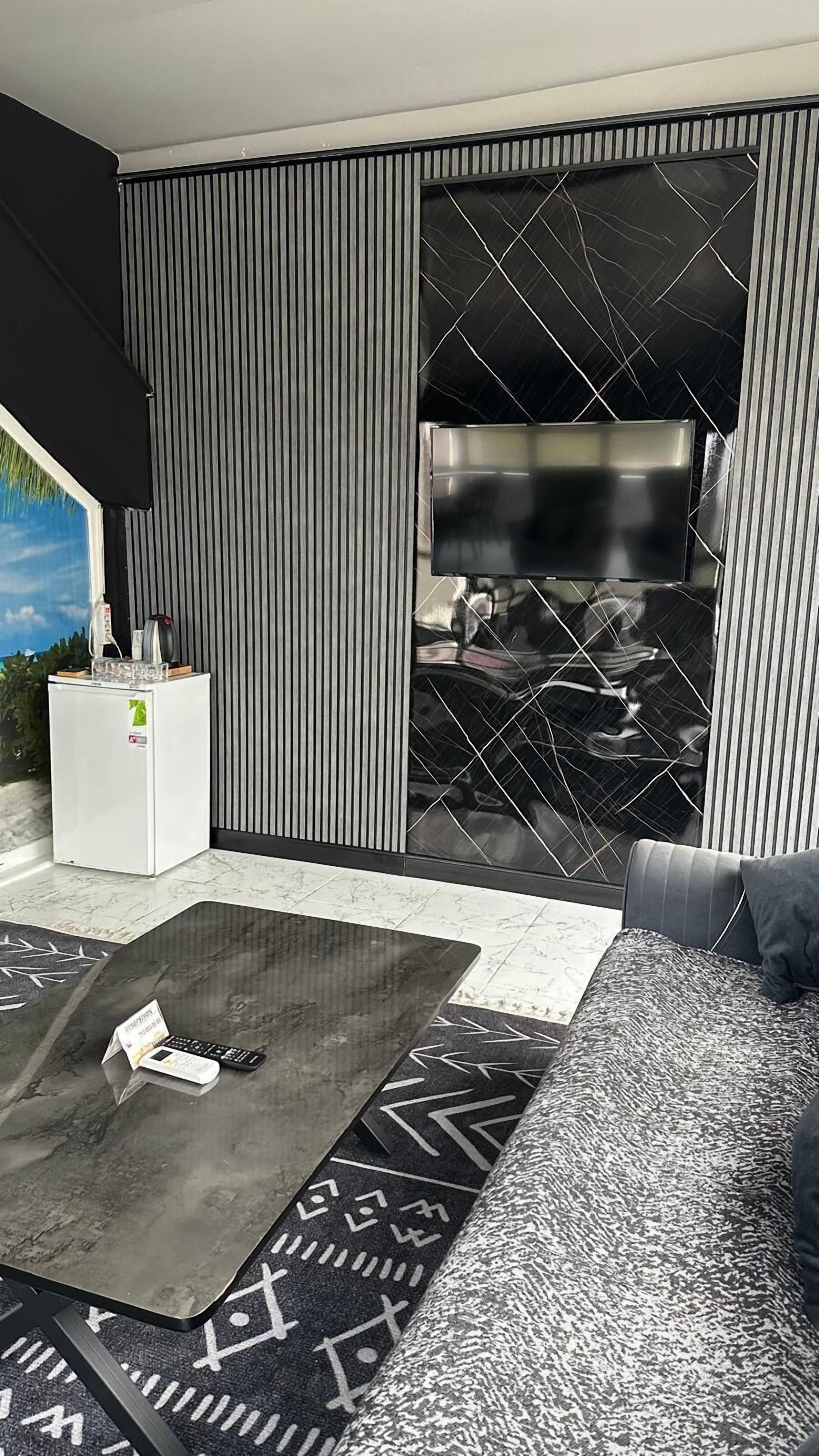 Una sala de estar moderna con un sofá, una mesa de centro, un televisor y un refrigerador.