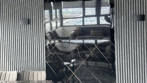 Una camera moderna con un'ampia porta-finestra scorrevole che dà su un balcone. All'interno, un tavolo di vetro con sedie e un divano.