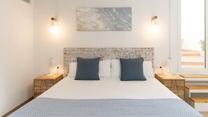 Un dormitorio moderno con una cama grande, dos mesitas de noche, un aire acondicionado de pared y una ventana con vistas.
