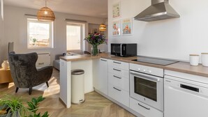 Una cocina moderna con armarios blancos, horno empotrado, microondas y campana extractora de acero inoxidable.