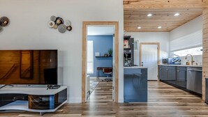 Una cocina moderna con una isla central, suelo de madera y vistas a un comedor.