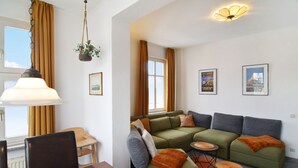 Ein modernes Wohnzimmer mit einer Eckcouch, einem Esstisch mit Stühlen und einer hängenden Pflanze.