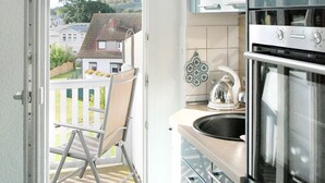 Eine moderne Küche mit einem Siemens-Ofen, einer Pendelleuchte und Blick auf einen Balkon mit Stuhl sowie ein Haus im Hintergrund.