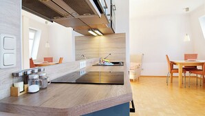 A modern kitchen with a wooden countertop, stainless steel appliances, and a dining area with wooden chairs and a table. - Villa Hamburg Appartement 08 (Seebad Ahlbeck)