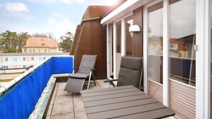 A balcony with a blue safety net, two lounge chairs, and a table. - Villa Hamburg Appartement 08 (Seebad Ahlbeck)