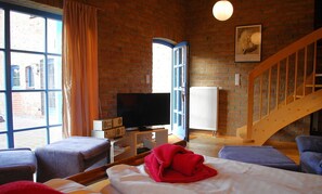 Relax in this inviting room with a large window offering a view of the outside, a flat-screen TV, and a comfortable seating area.