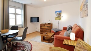Een moderne woonkamer met een bank, salontafel, televisie en een eethoek met stoelen en een tafel.