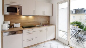 Een moderne keuken met een ingebouwde magnetron, een koffiezetapparaat en een broodrooster. Een groot raam biedt uitzicht op buiten.