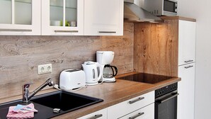 Eine moderne Küche mit weißen Schränken, einer Holz Arbeitsplatte, einer eingebauten Mikrowelle und einer Kaffeemaschine.